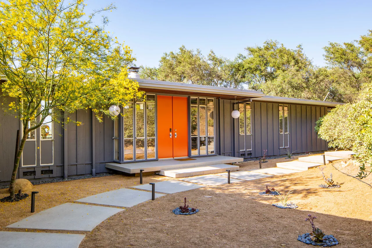 Front of the house: board-and-batten siding, globe pendants and double doors behind floating steps