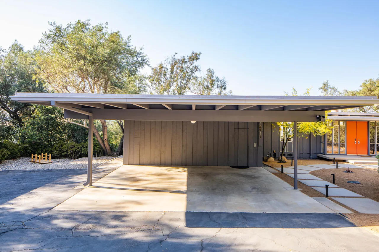 Carport beneath a wide, flat roofline with the front doors beyond
