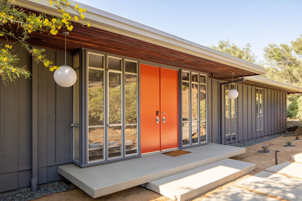 Vermilion double entry doors, globe pendants and redwood soffit in daylight