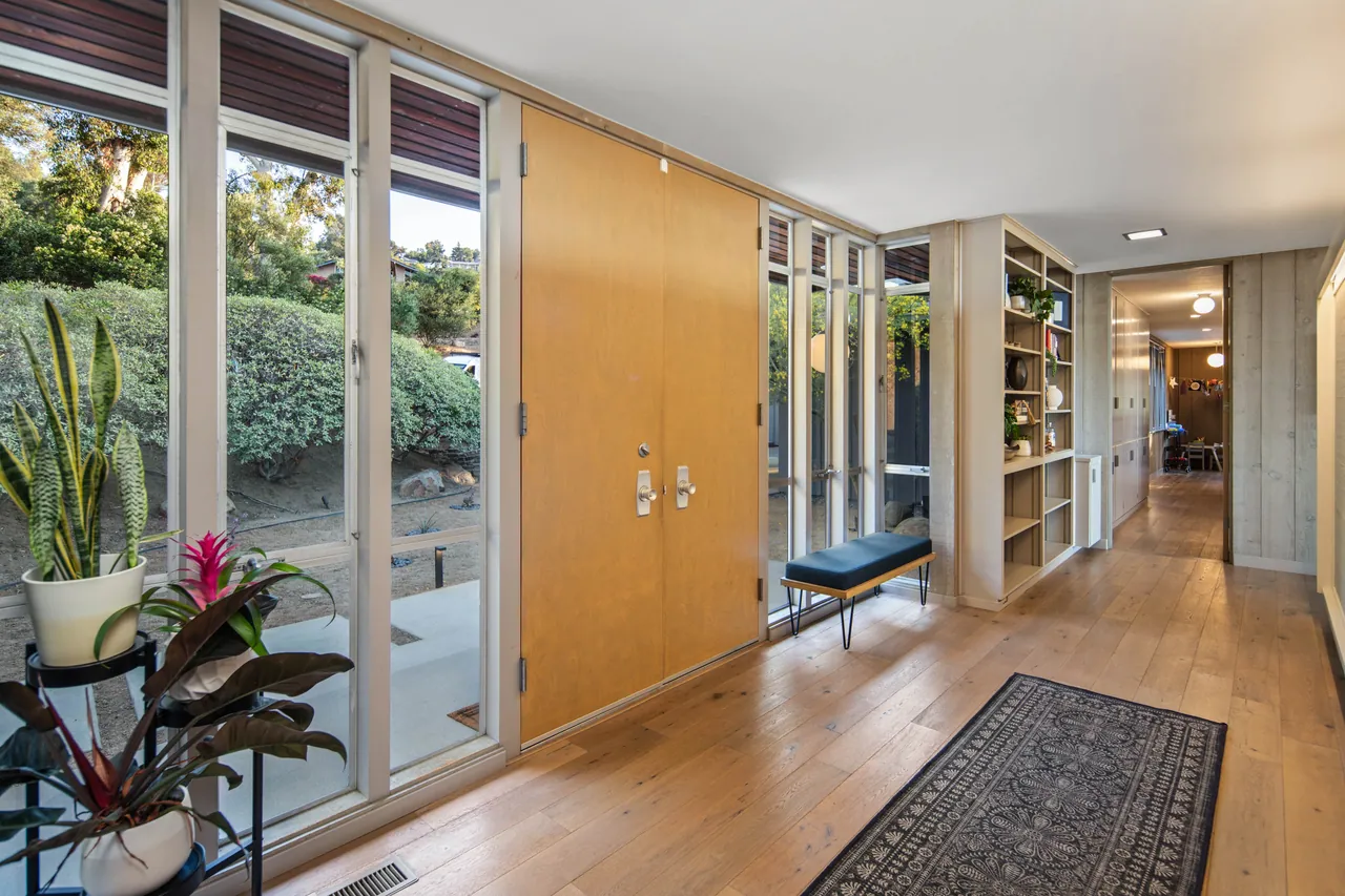 Entry gallery with a glass wall, wood-paneled doors and built-in shelving