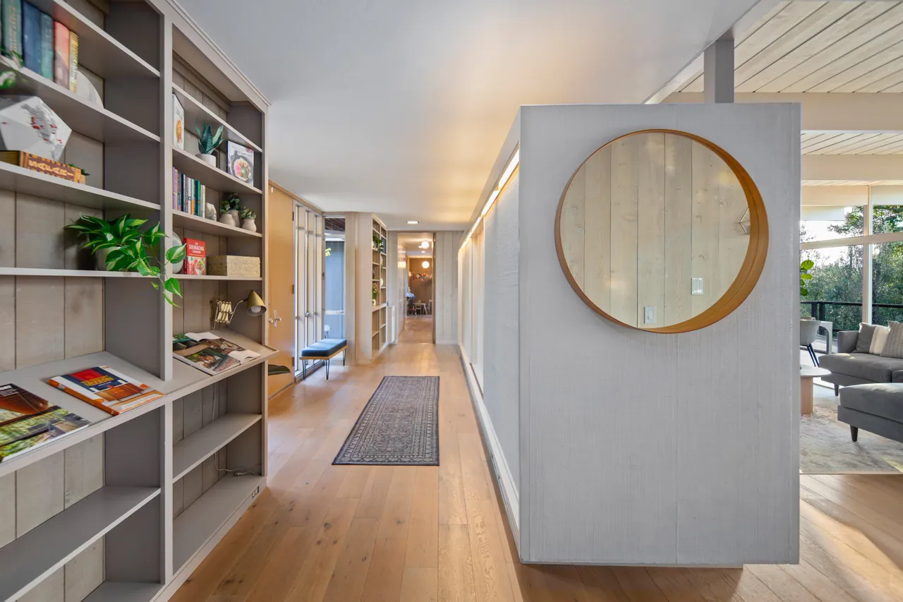 Entry gallery lined with built-in bookshelves and a round mirror