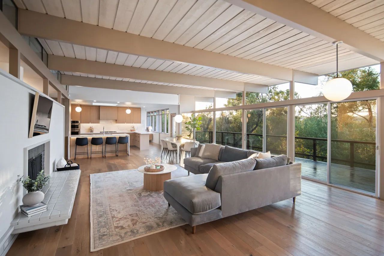 Great room under open beams with a full wall of glass toward the valley